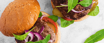 A burger in a bun with salad and sesame seeds