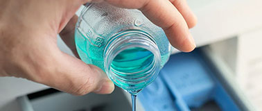Uomo che versa il liquido di lavaggio concentrato nella macchina