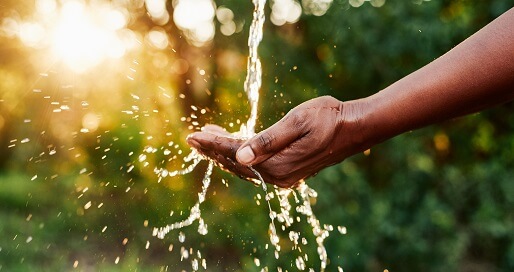 A man catching a stream of water in his hand in the sunset
