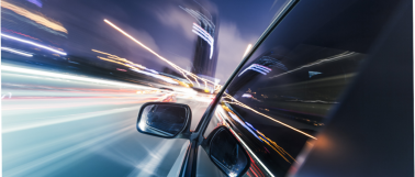 Car driving down city street with light trails