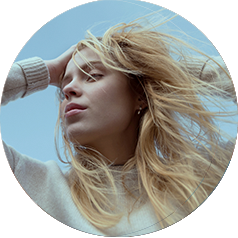 A woman stands outside as the wind rushes through her long blonde hair.
