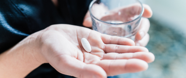person holding pills with a glass cup