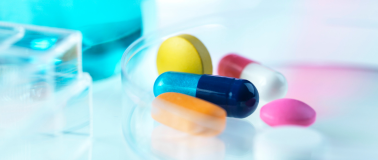 blue solution in the background with various of shapes, sizes and colors of prescription pills in focus